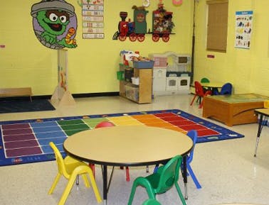 Empty classroom with small tables and chairs, colorful rug