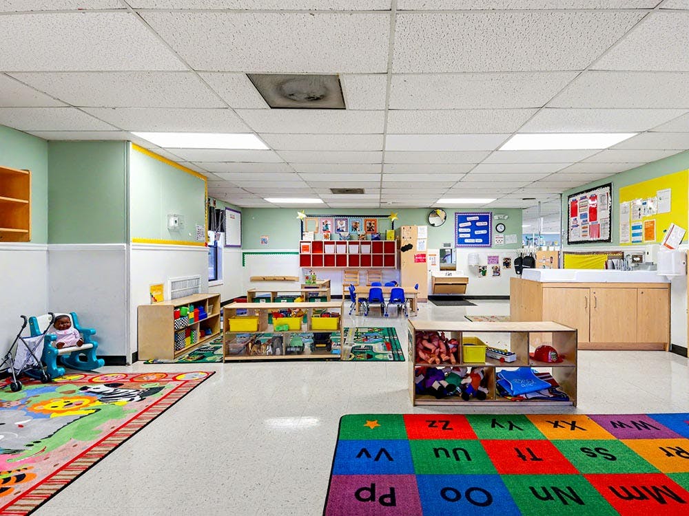 Classroom with colorful rugs, low shelves, and child-sized furniture