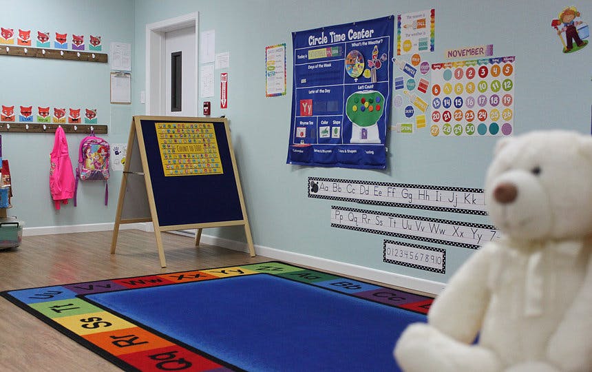 Classroom with a colorful rug, easel, and educational posters on the wall