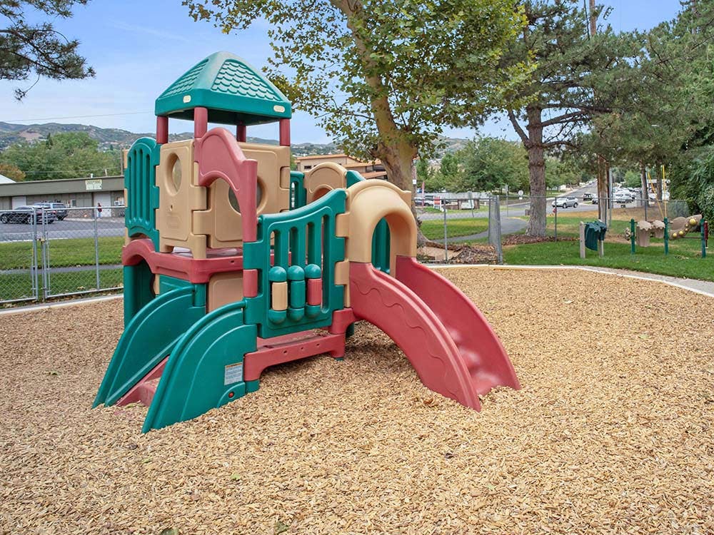 Playground structure with slides and climbing area on wood chip ground