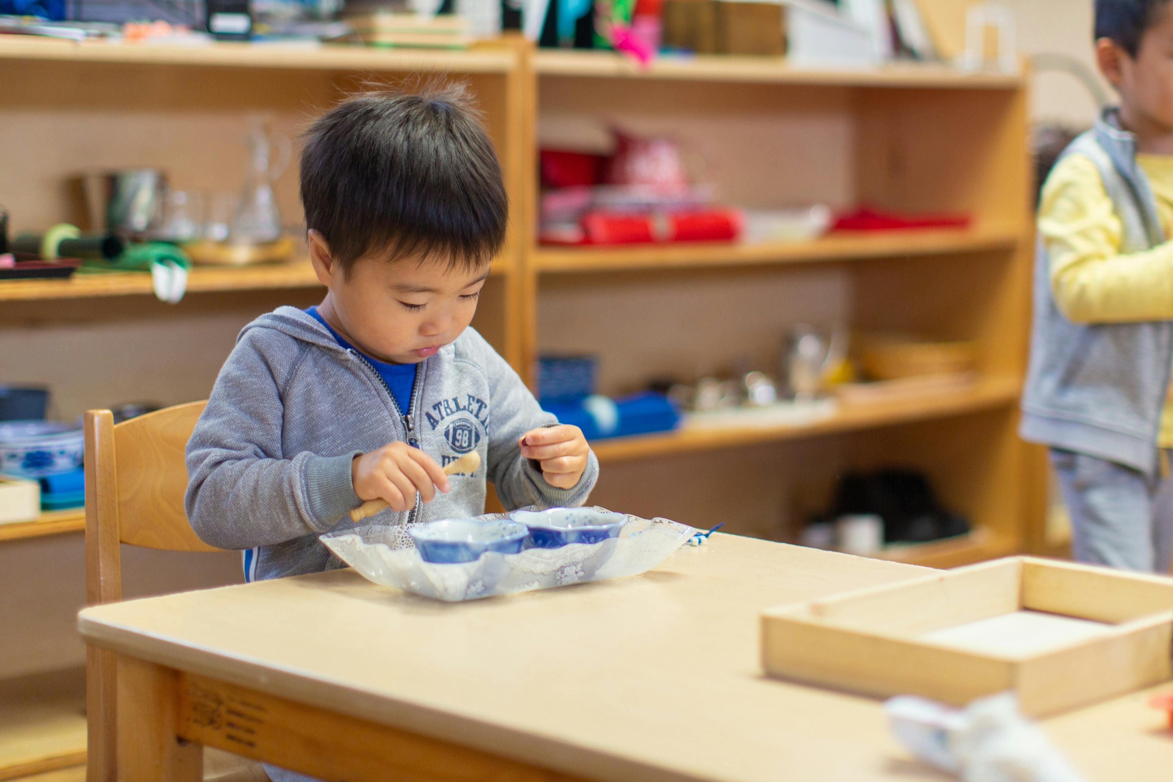Child sitting at a table and manipulating an object in a classroom
