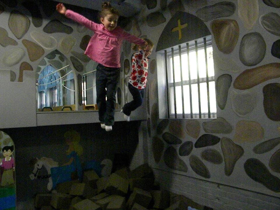 Two children jumping from a ledge into a foam pit