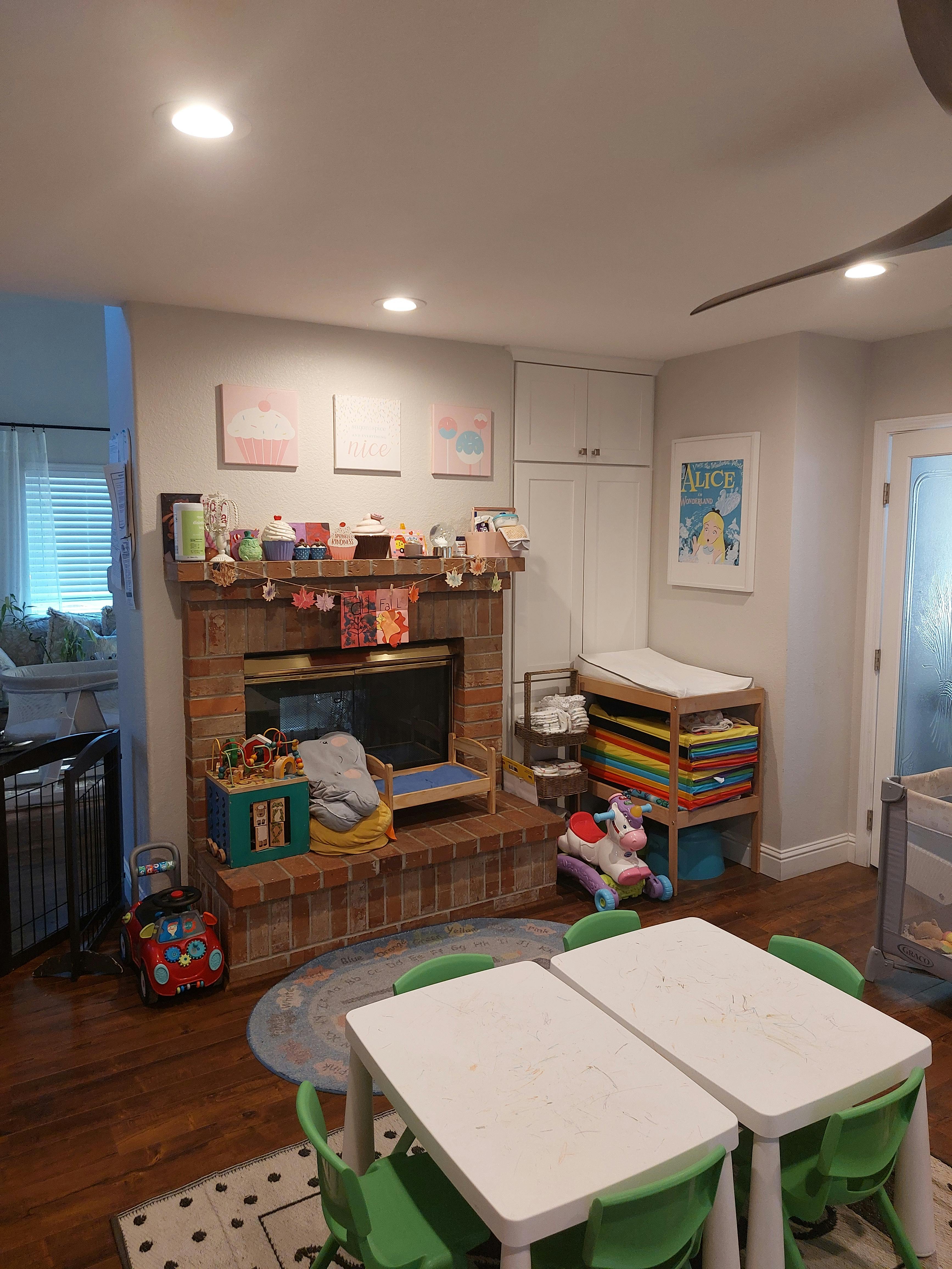 Playroom with small tables and chairs, a fireplace, and a changing table