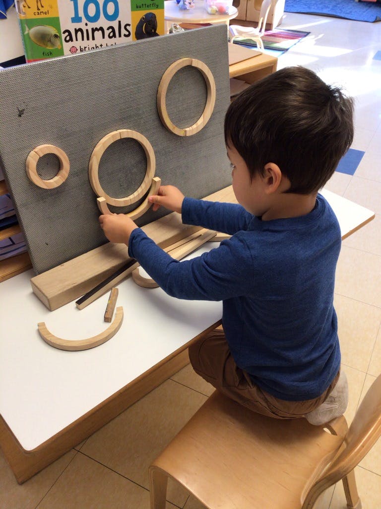 Child playing with wooden rings on a gray board