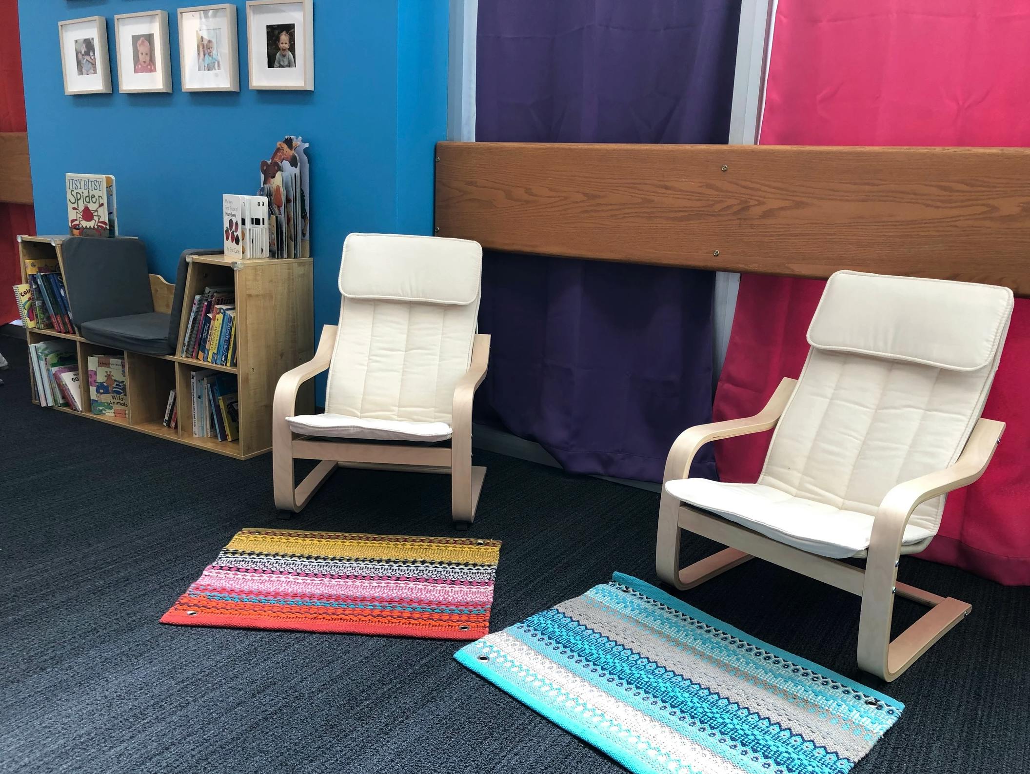 Two chairs and two rugs in a room with a bookshelf