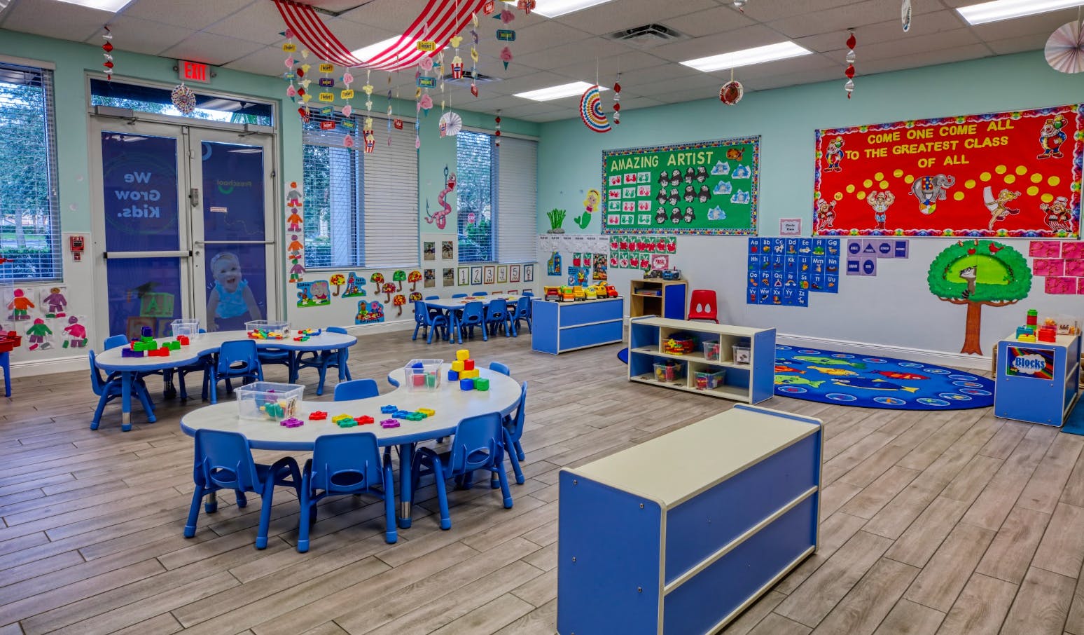 Colorful classroom with blue tables and chairs, wall decorations, and learning materials