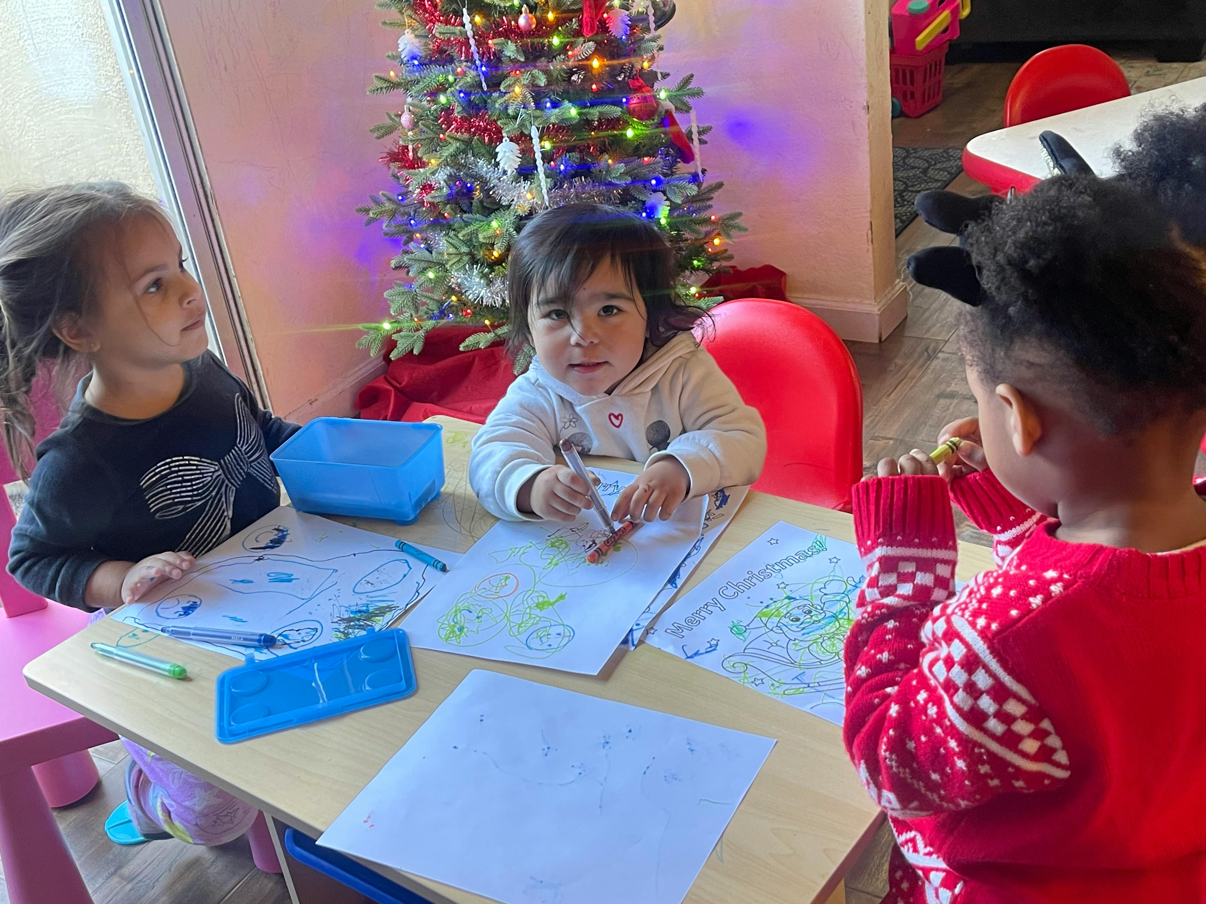 Three children drawing at a table
