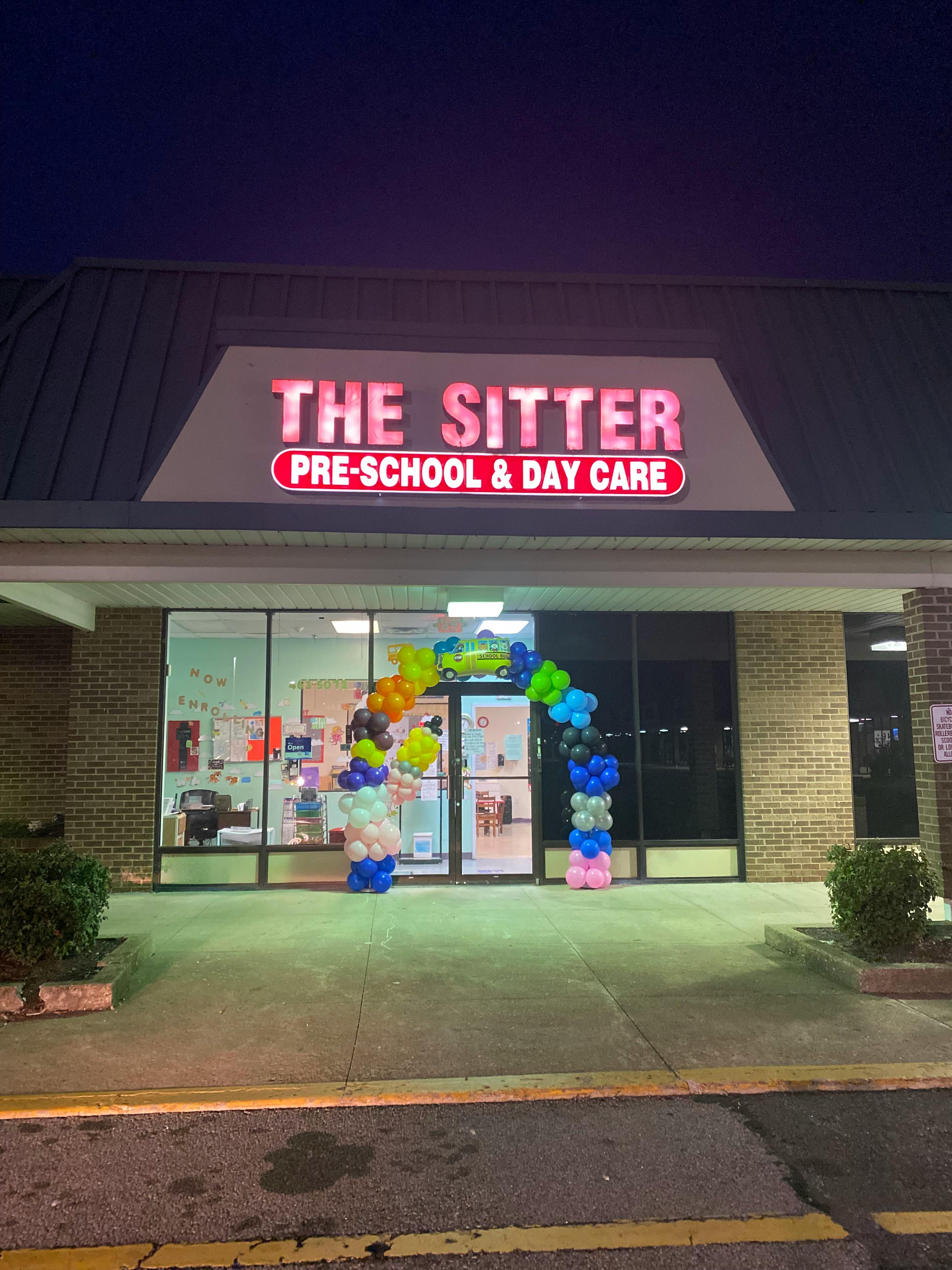 The Sitter Pre-School & Day Care sign above an entrance with a balloon arch