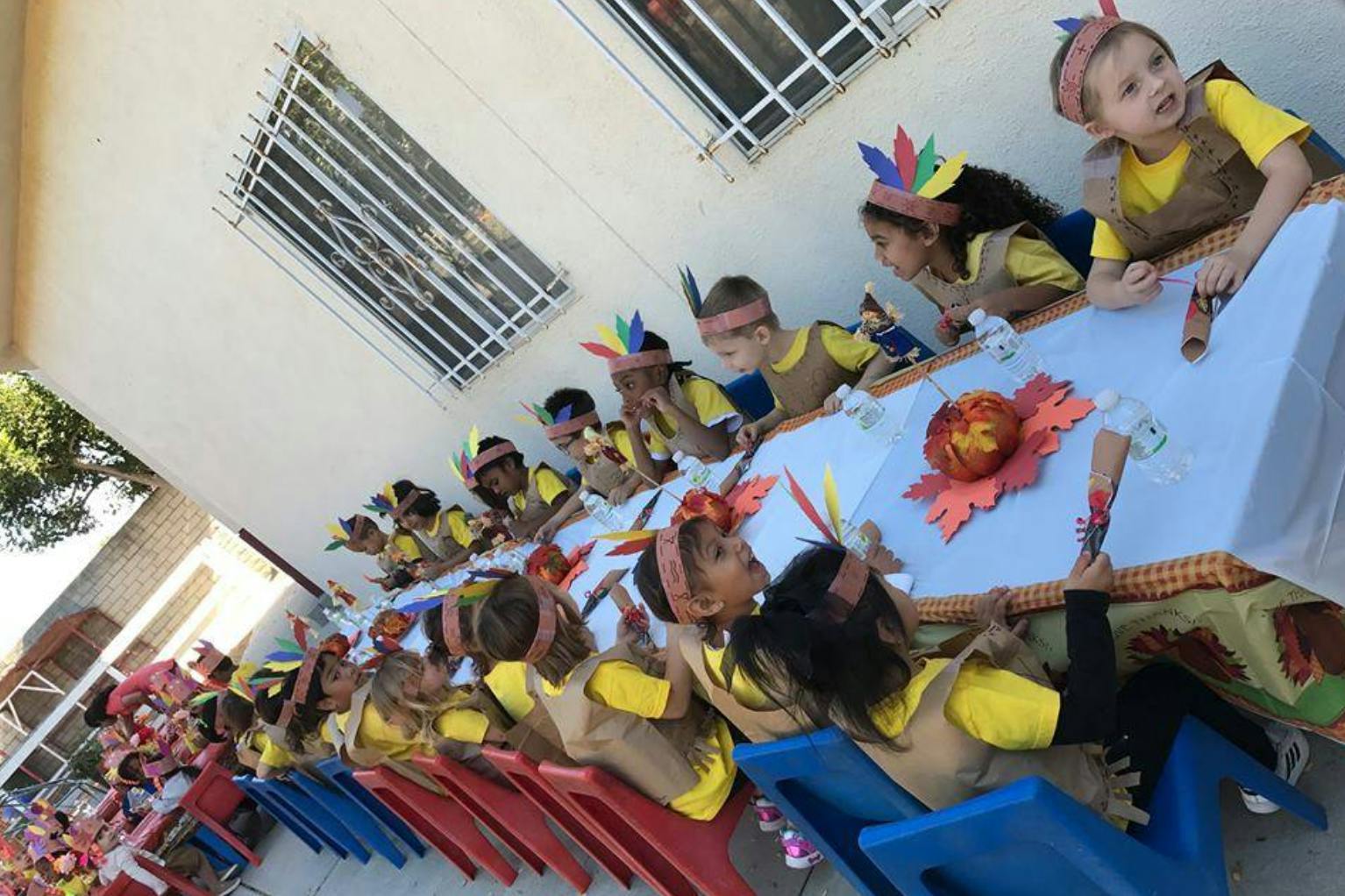 Children in costumes sitting at a long table outdoors