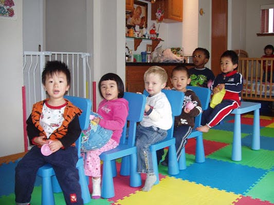Group of children sitting on small blue chairs in a classroom