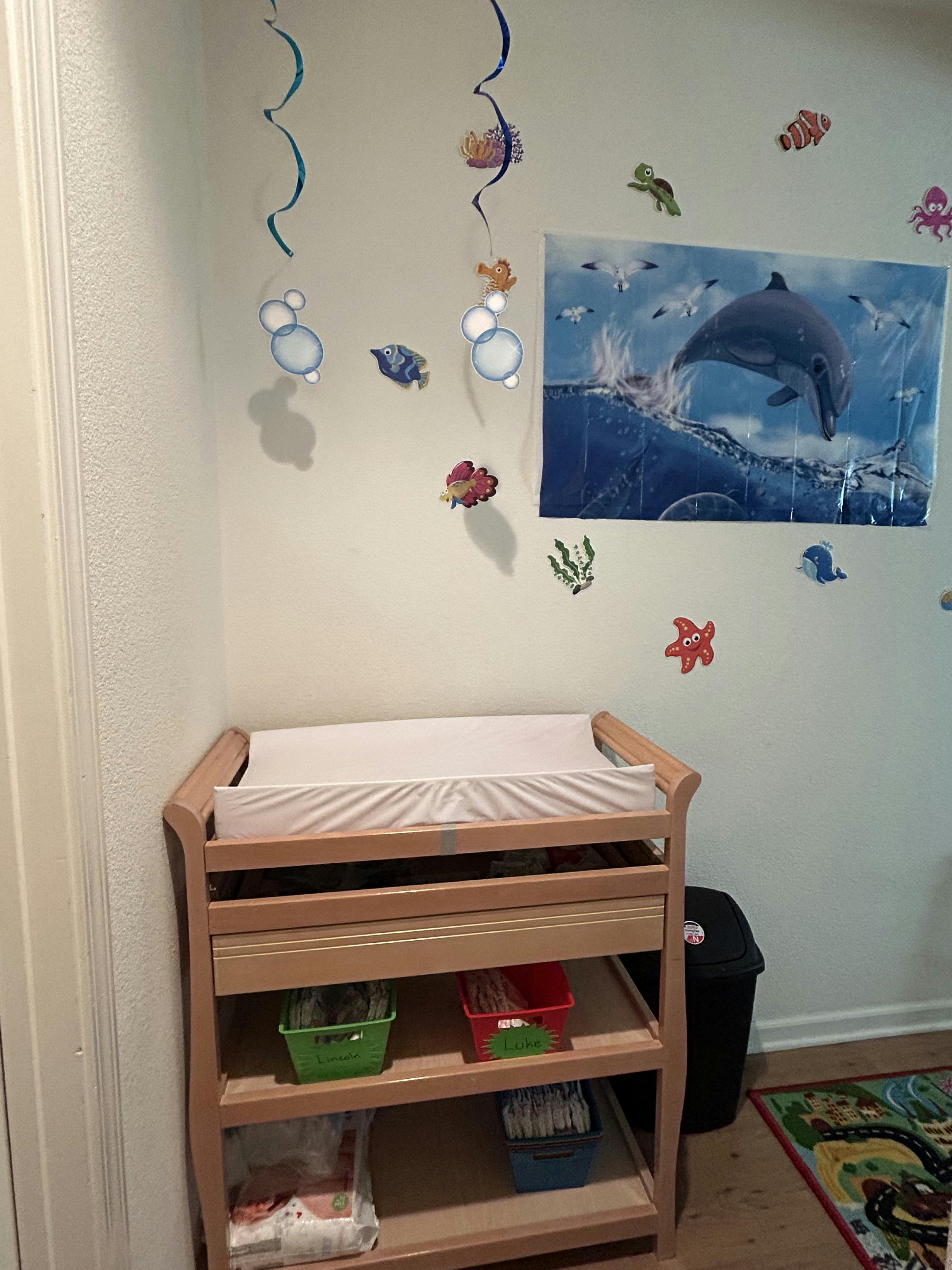 Changing table with a dolphin poster and sea-themed wall decorations