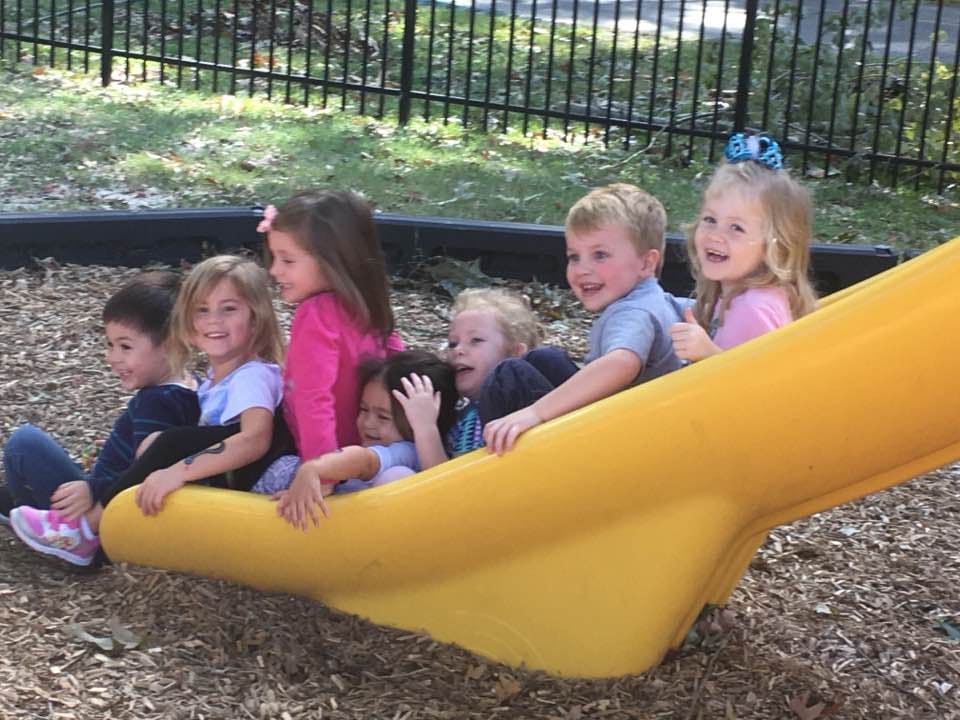 Group of children sitting on a yellow slide