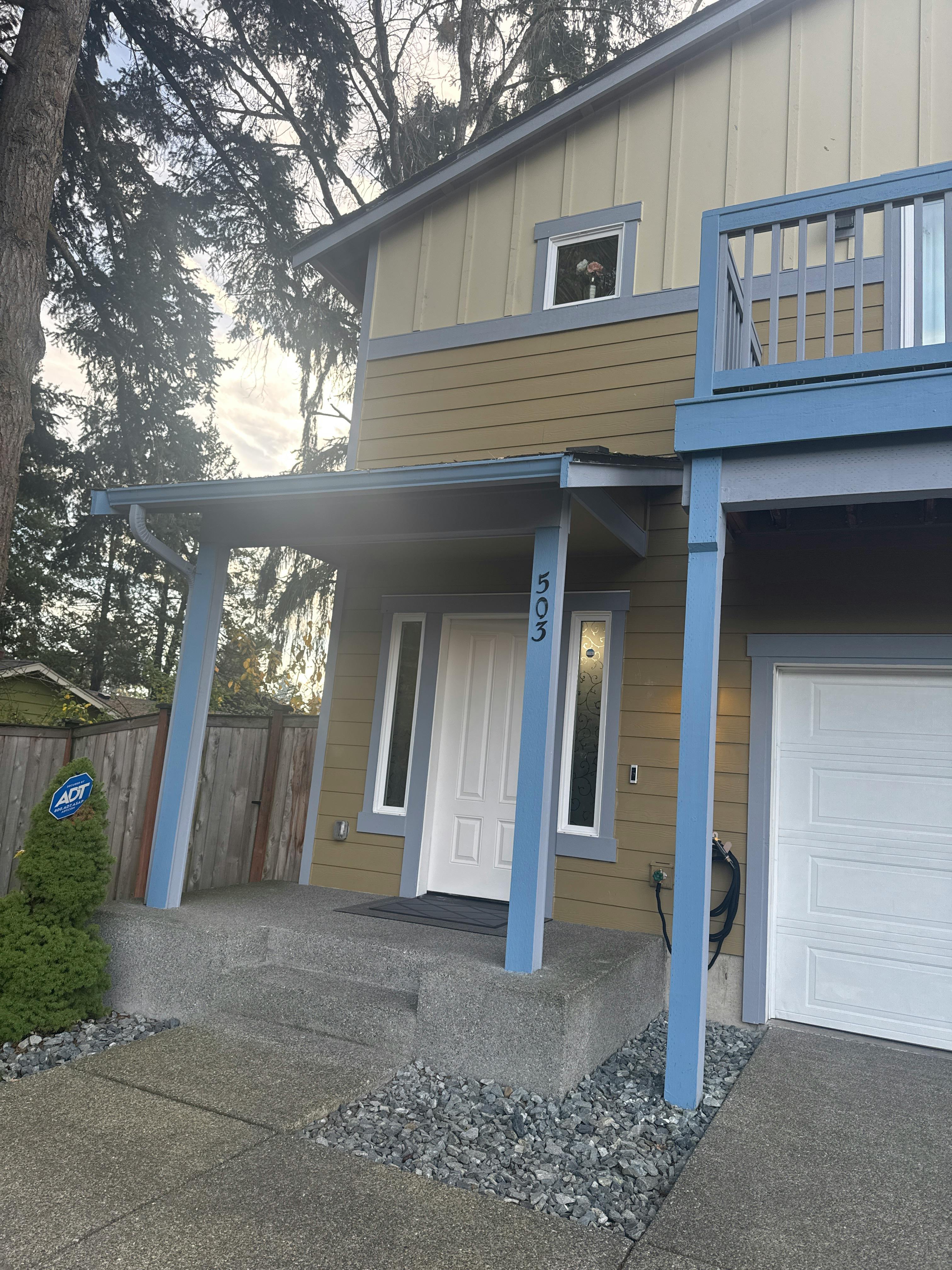 Front exterior of a house with a white door and garage, blue trim, and number 303