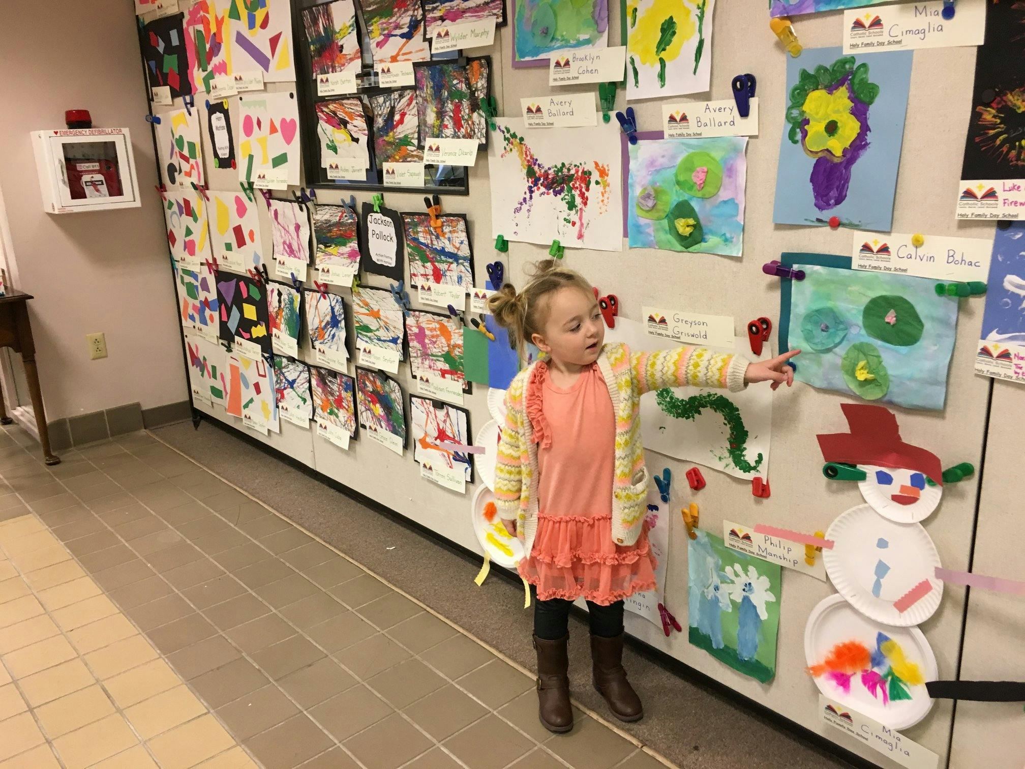Child pointing at artwork on a wall