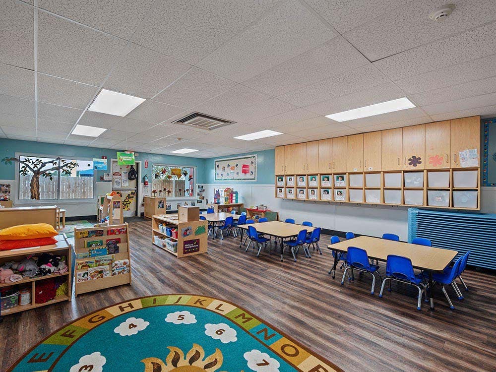 Empty colorful preschool classroom with small tables and chairs