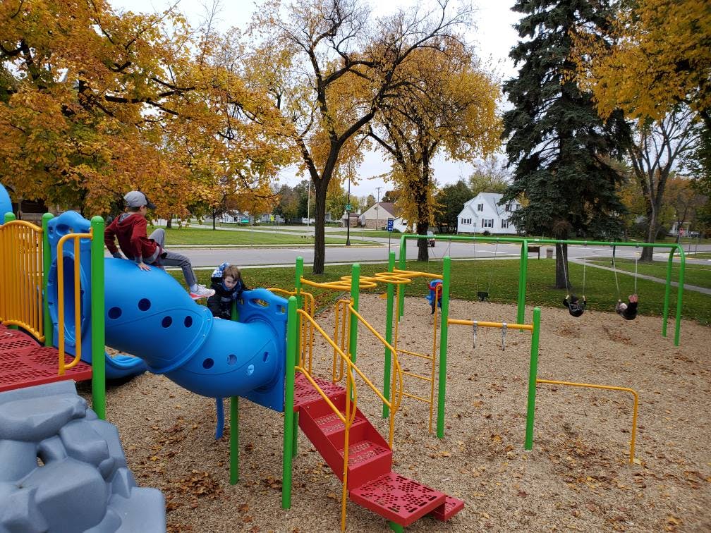 Two children on a blue slide at a playground