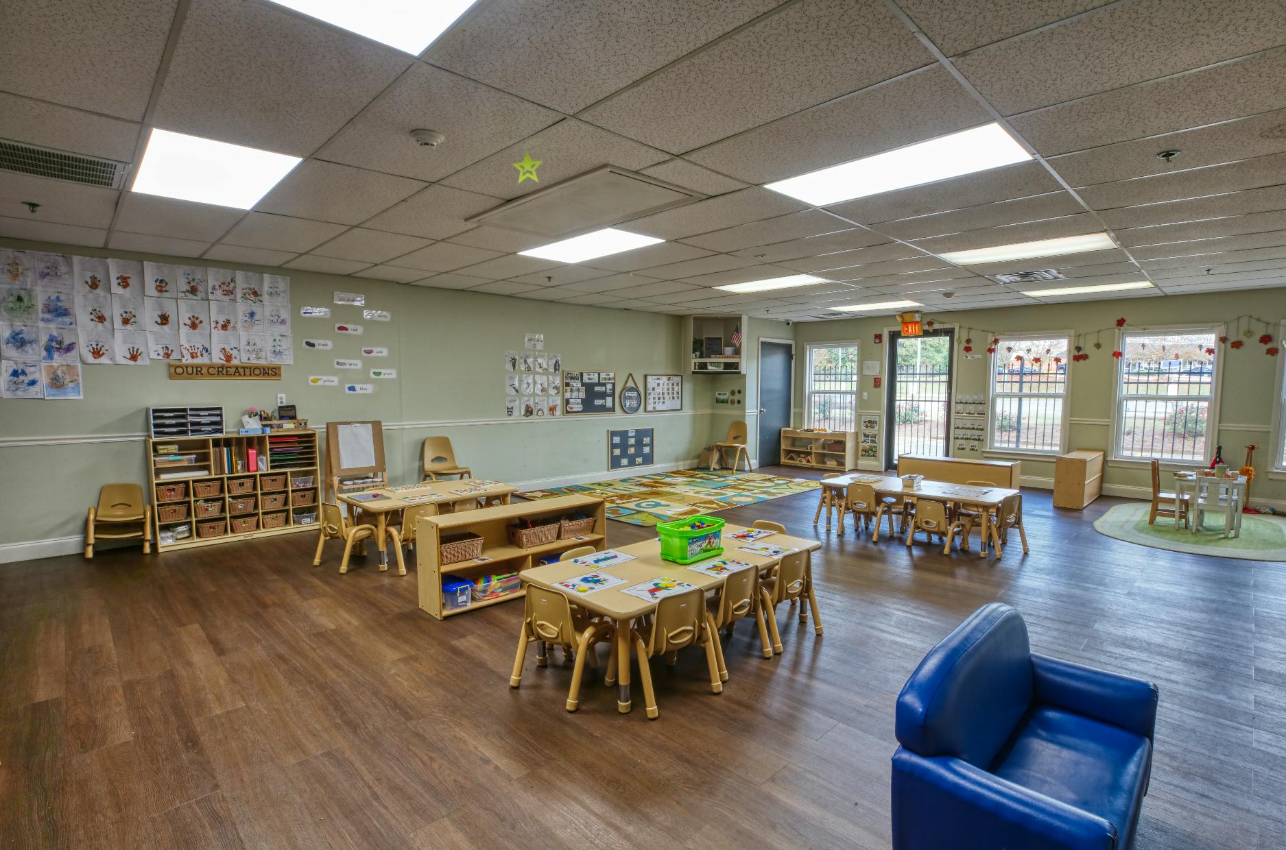 Classroom with small tables and chairs, shelves, and artwork on the walls