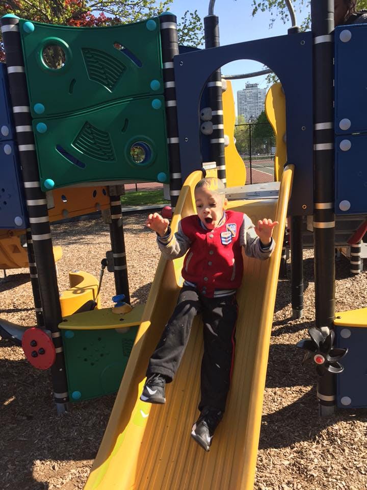 Child sliding down a yellow slide on a playground