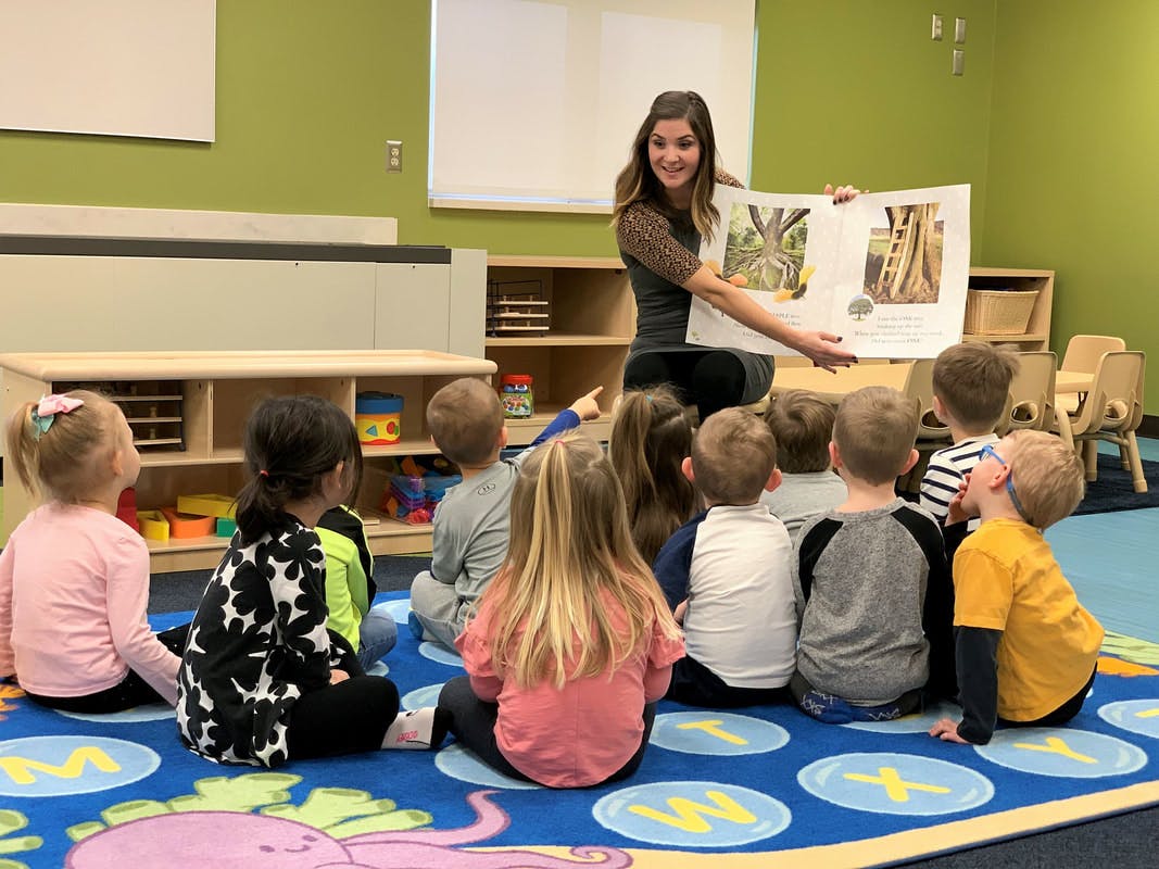 Person reading a book to a group of children in a classroom