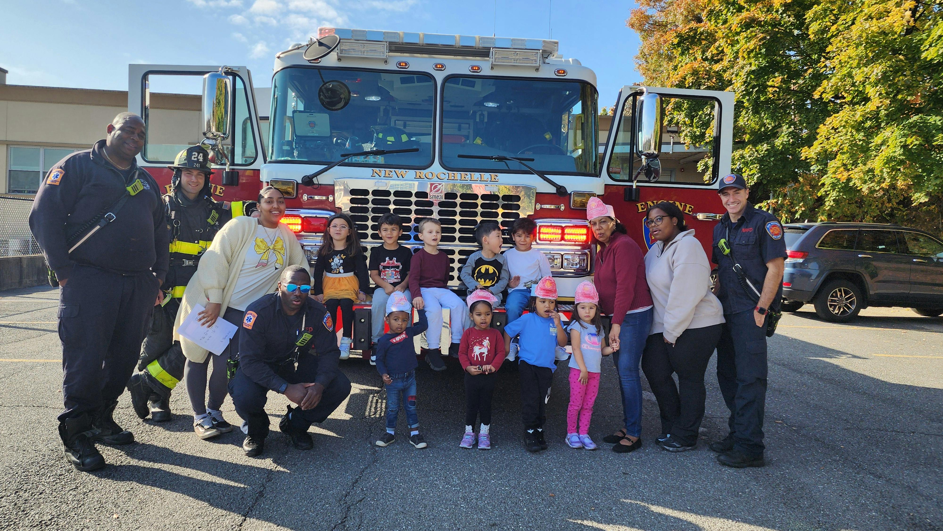 Adults and children posing in front of a fire truck