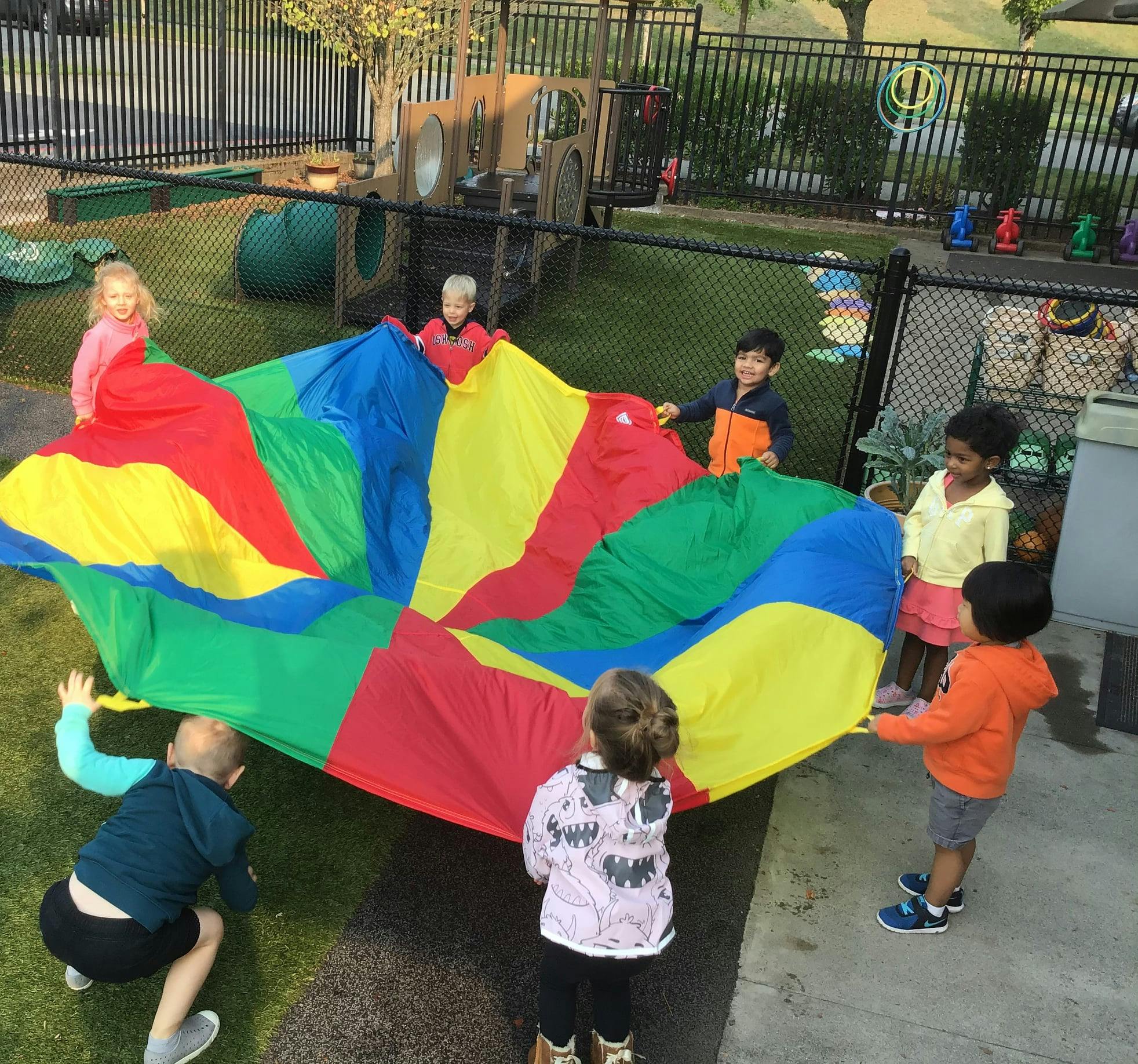 Children playing with a colorful parachute outdoors