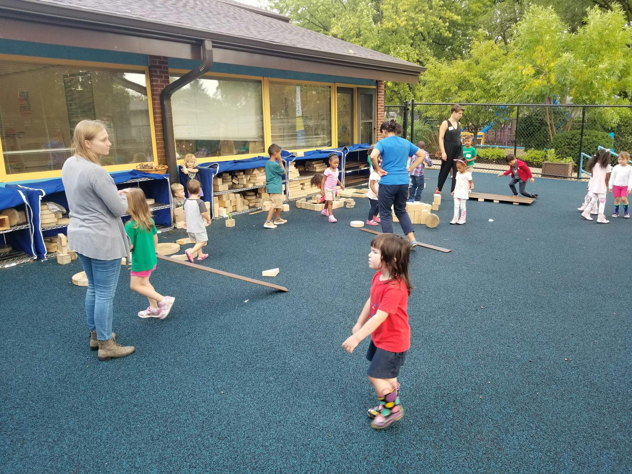 Adults and children playing outdoors on a blue surface
