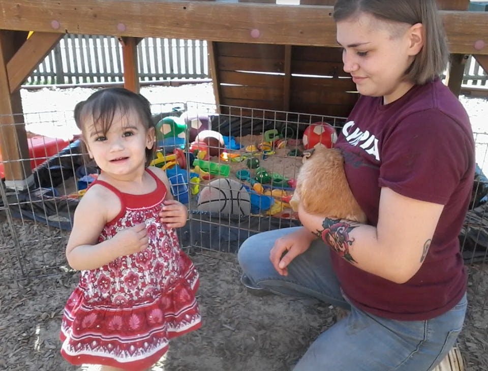Person holding a chicken next to a child