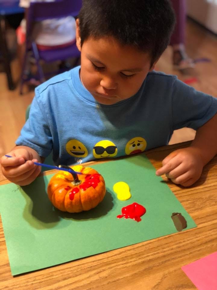 Child painting a small pumpkin red