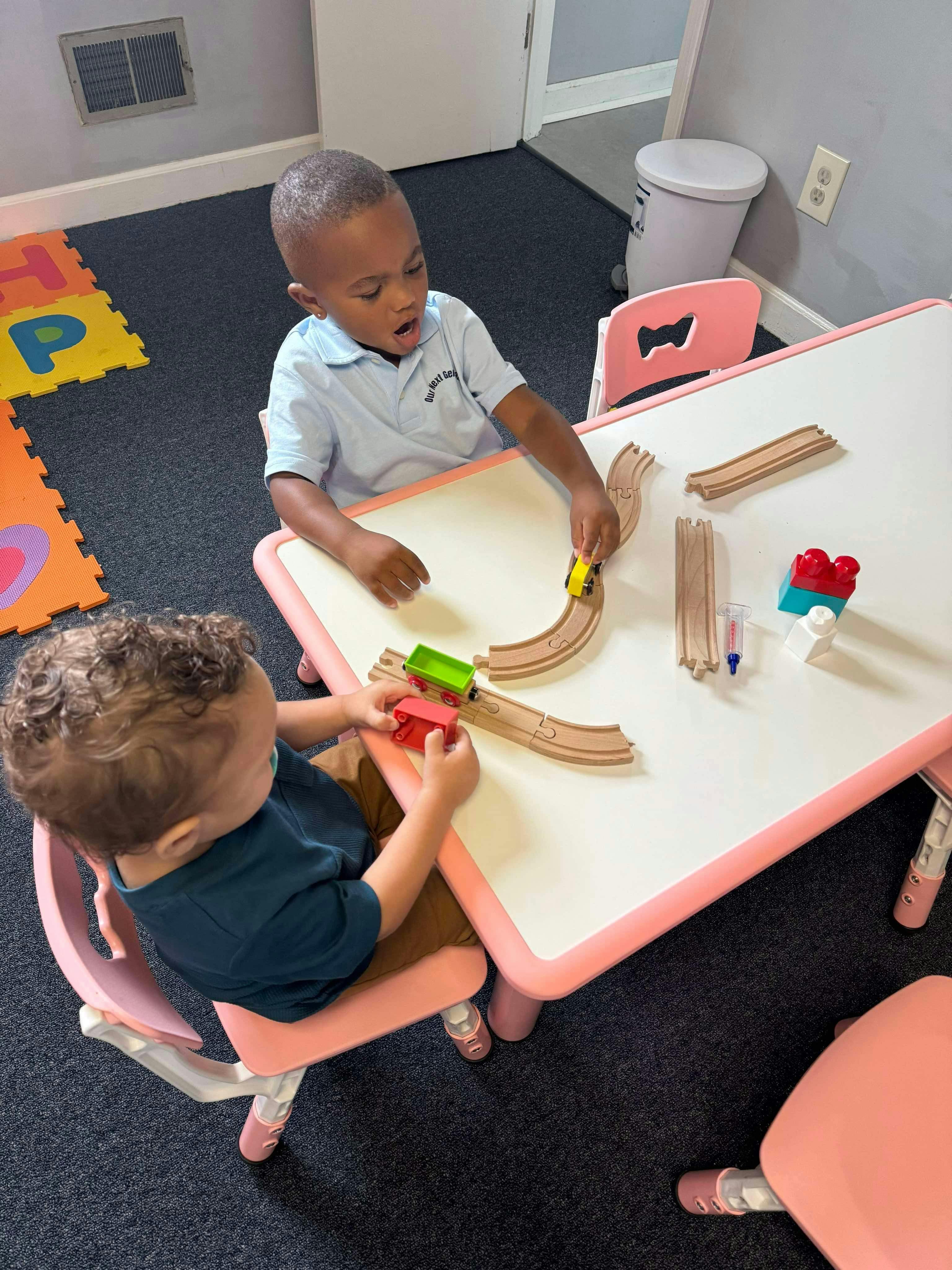 Two children playing with a toy train set on a table