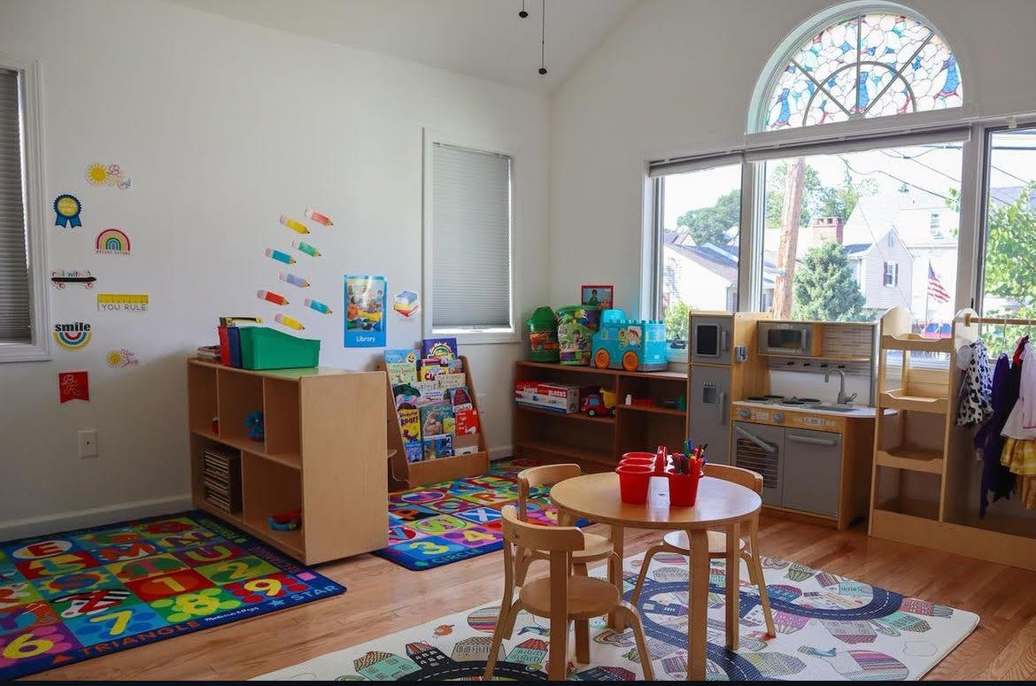 Playroom with small table and chairs, toy kitchen, and colorful rugs