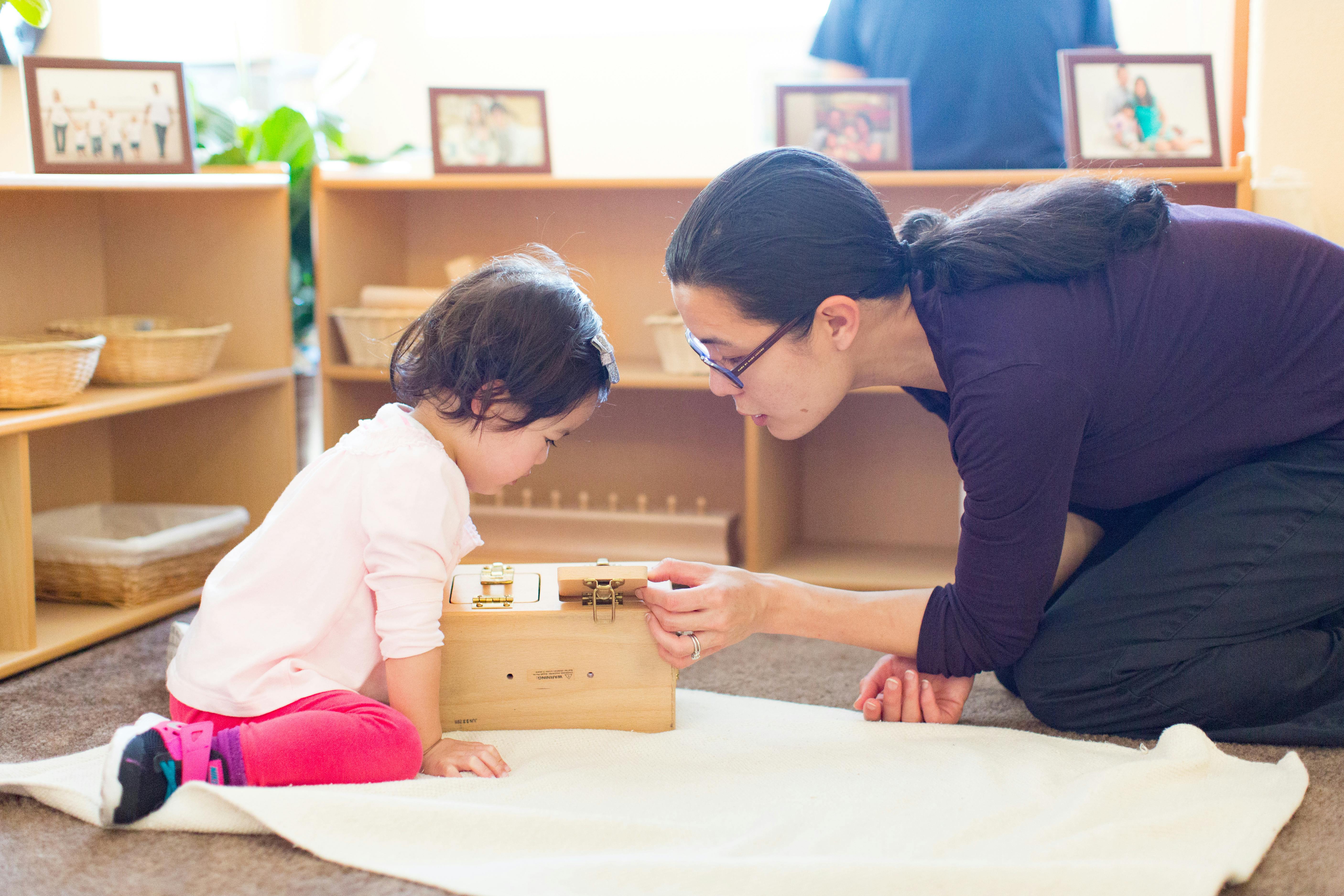 Person and child kneeling, looking at a wooden box