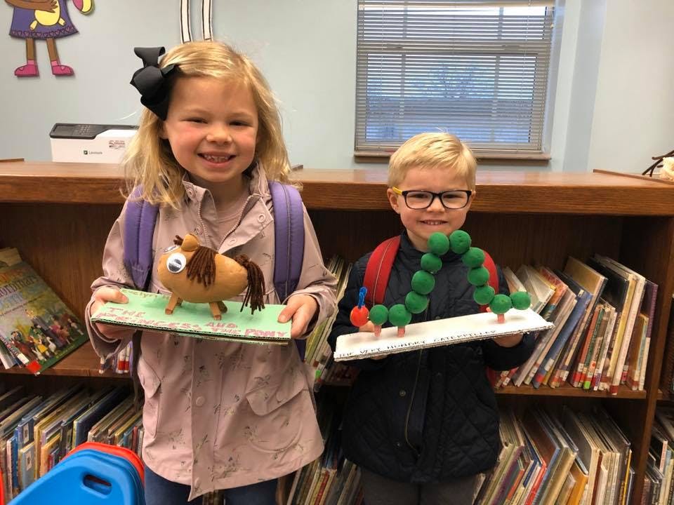 Two children holding up their school projects