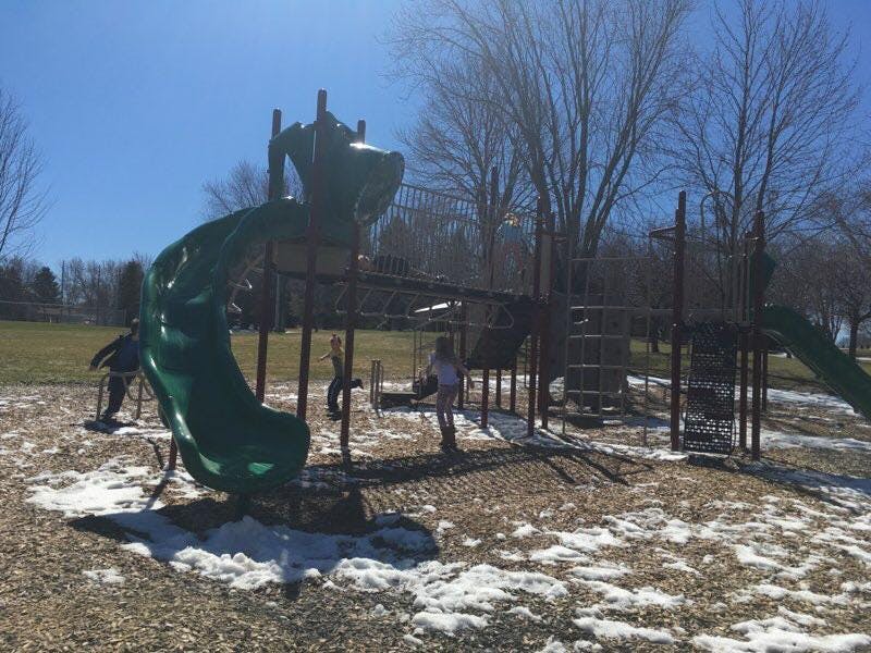Playground with slides and climbing structures on a partially snow-covered ground