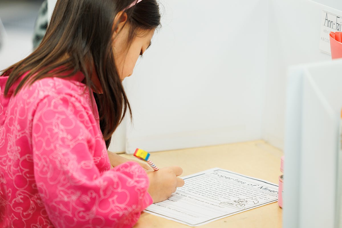 Child writing on paper at a desk