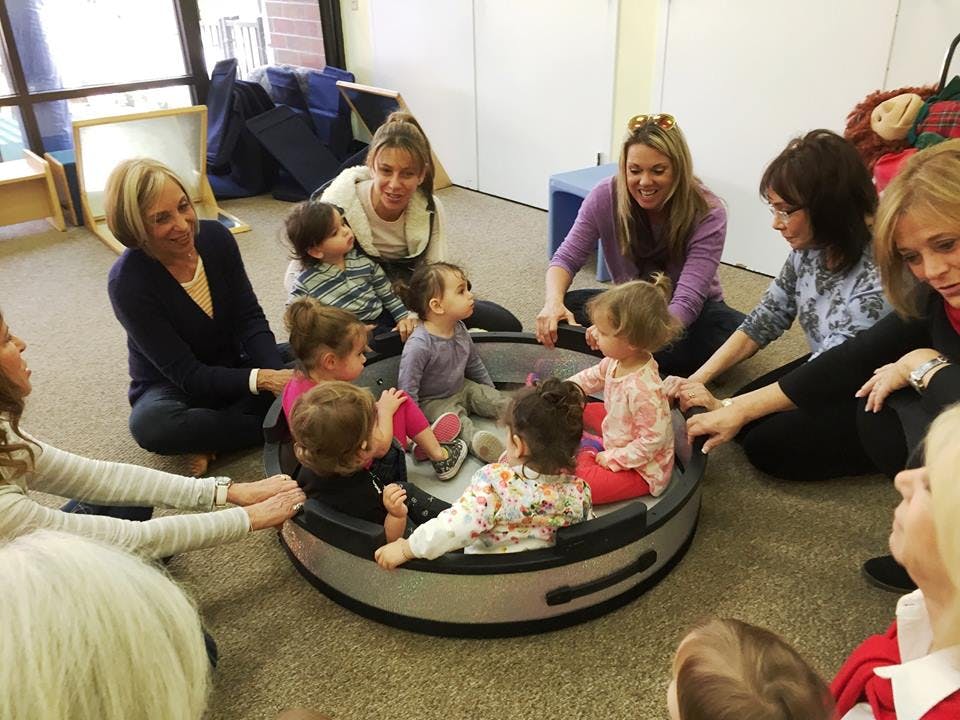 Adults and children sitting in a circle around a playpen