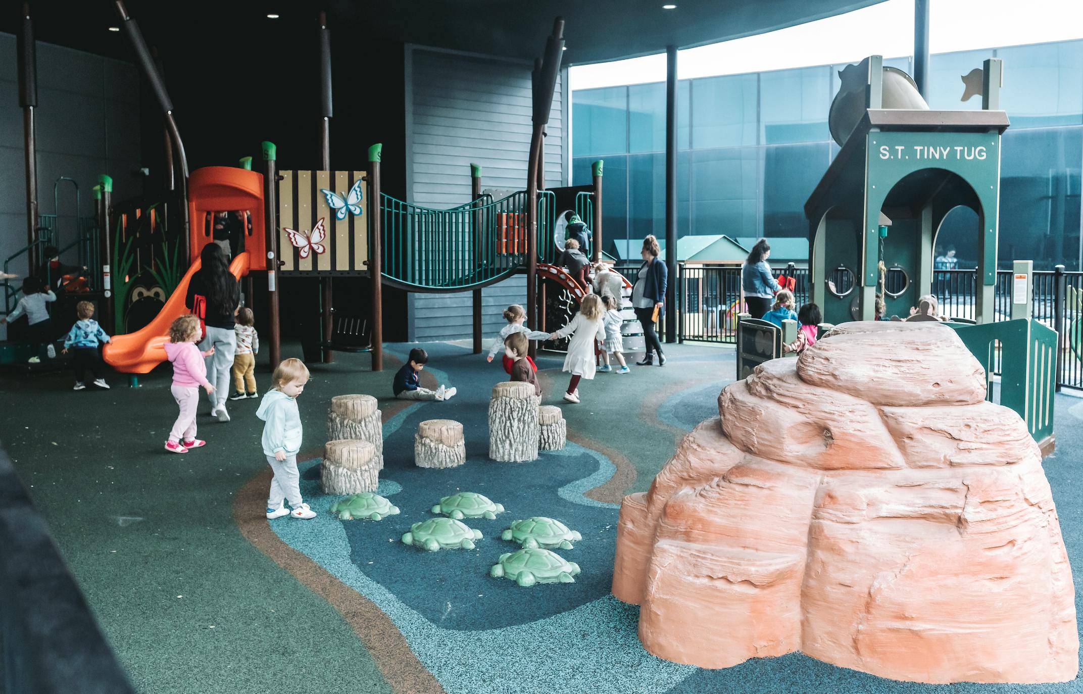Children playing on an indoor playground with slides and climbing structures