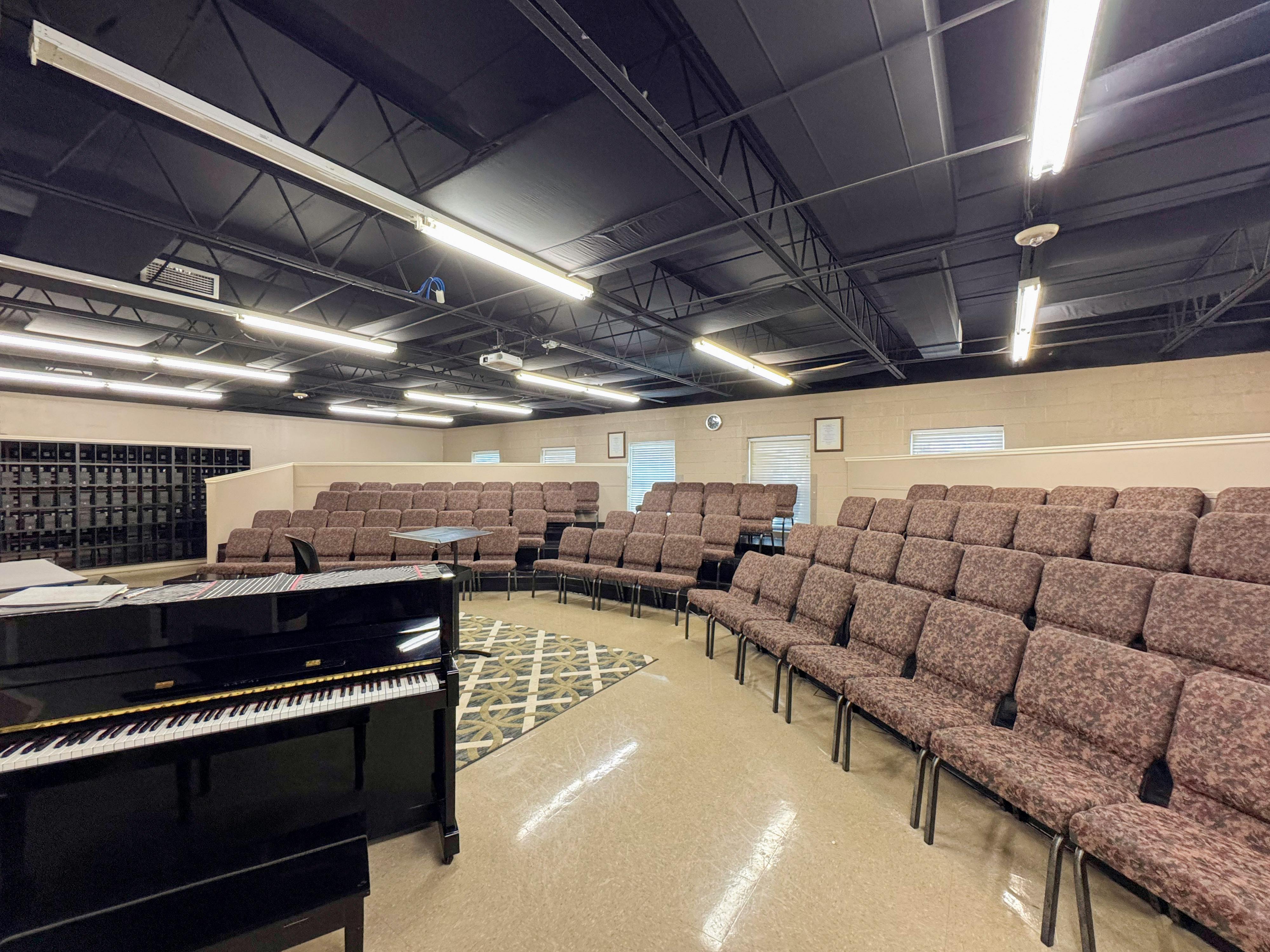 Black grand piano in a room with rows of empty chairs