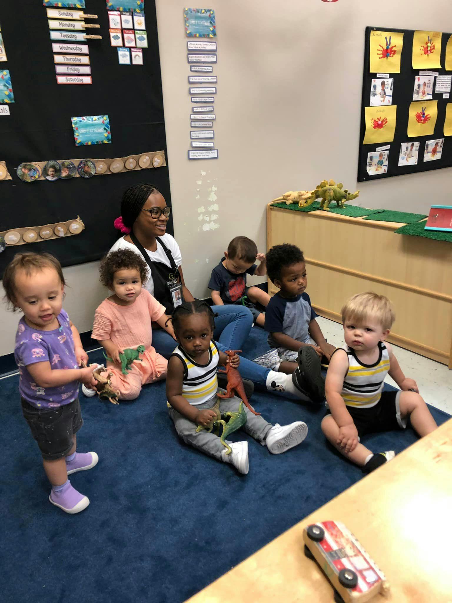 Adult and multiple children sitting on a blue carpet in a classroom