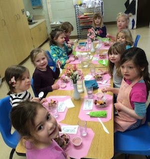 Children sitting at a table with food and drinks