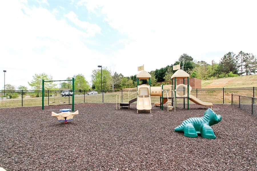 Playground with slides, swings, and a dinosaur-shaped climbing toy