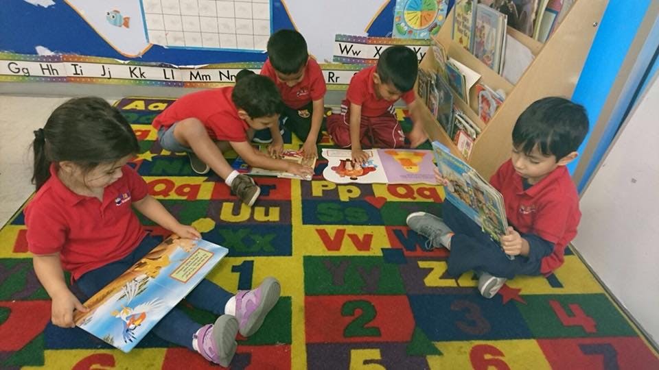 Children reading books on a colorful alphabet rug in a classroom