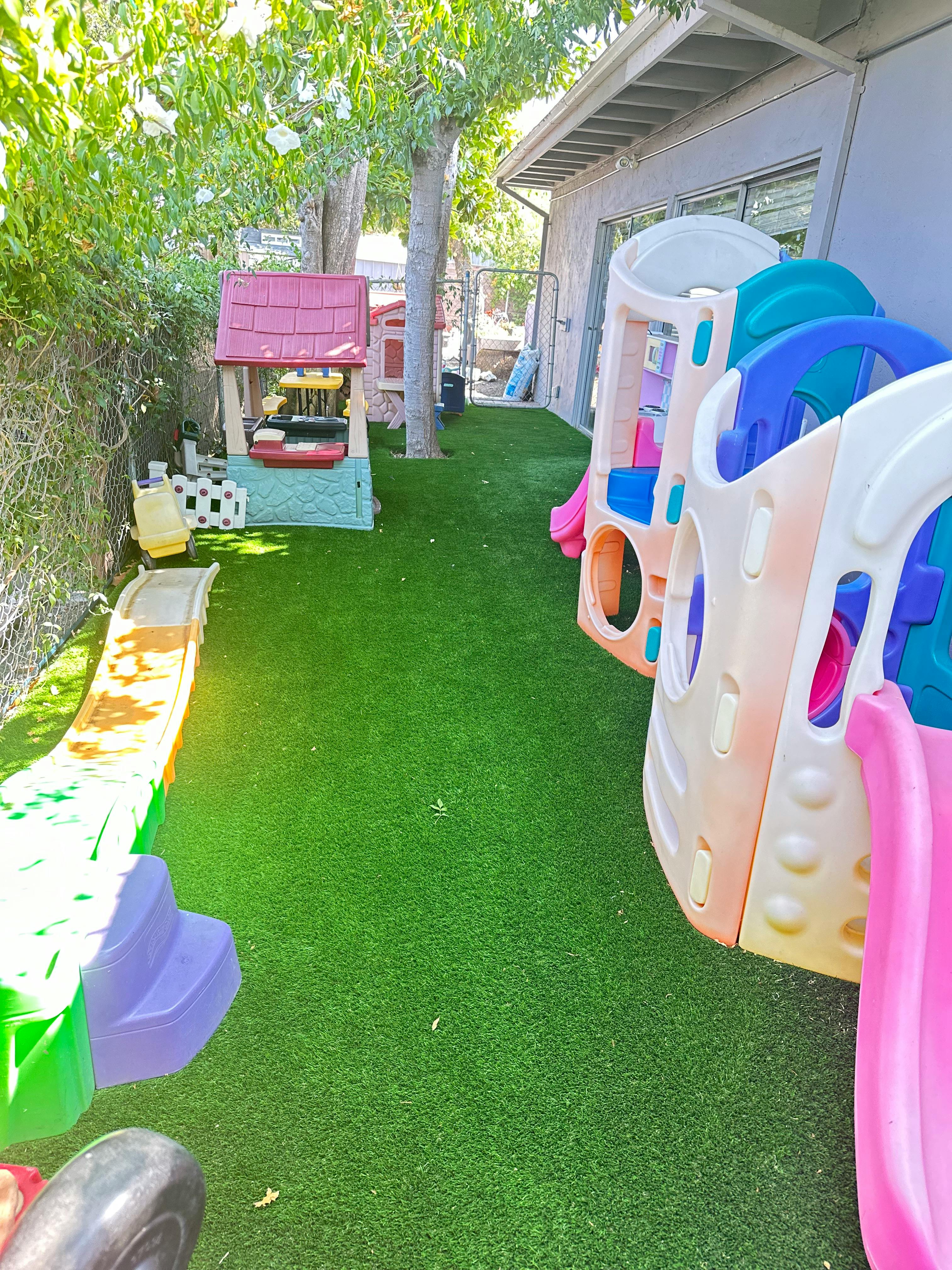 Playground with multiple slides and a playhouse on artificial turf