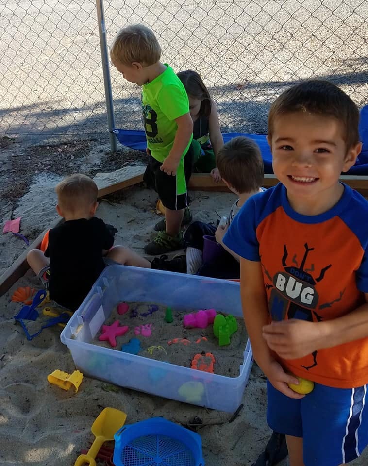 Children playing in a sandbox with toys