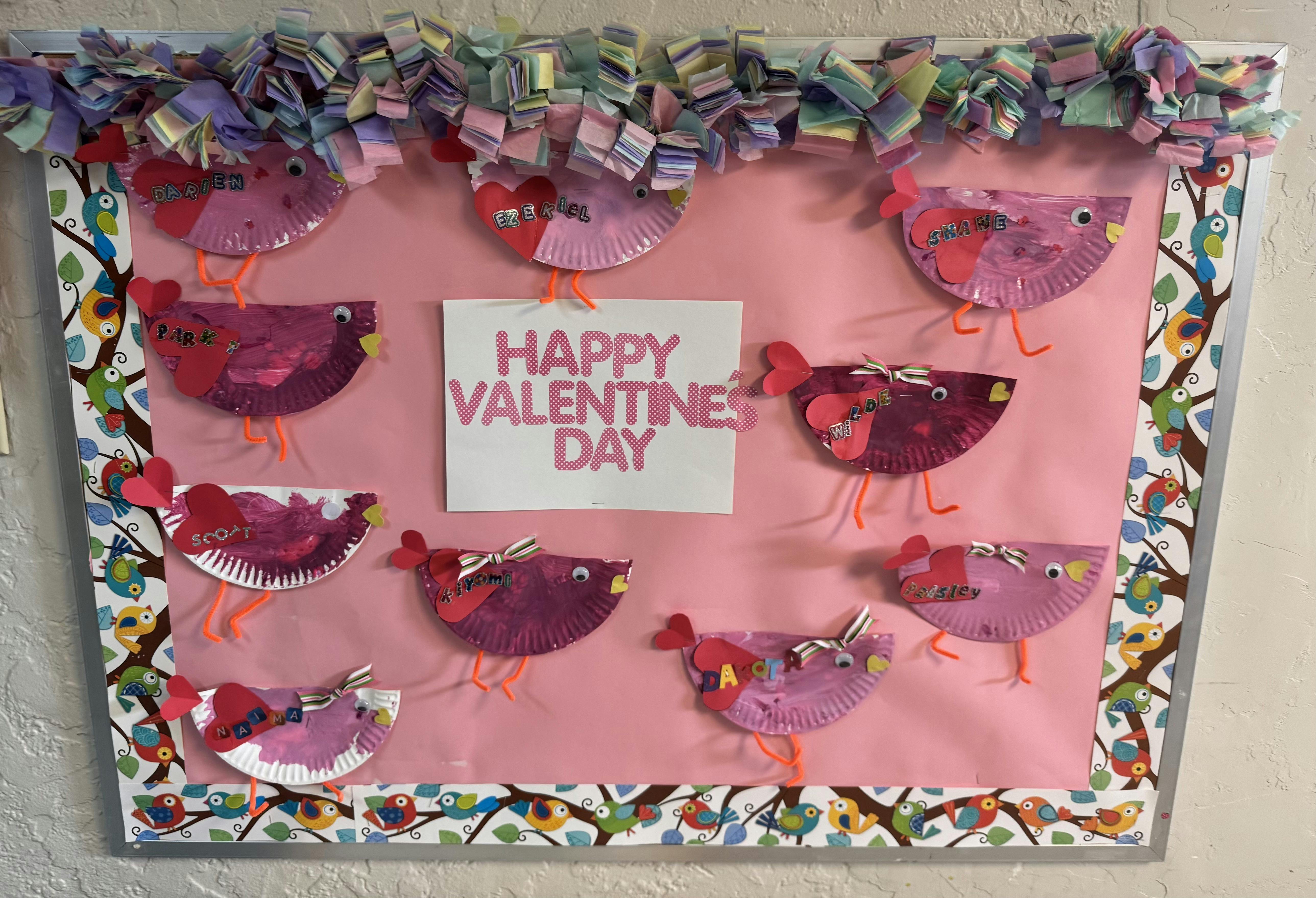 Children's paper plate birds on a bulletin board with "Happy Valentine's Day"