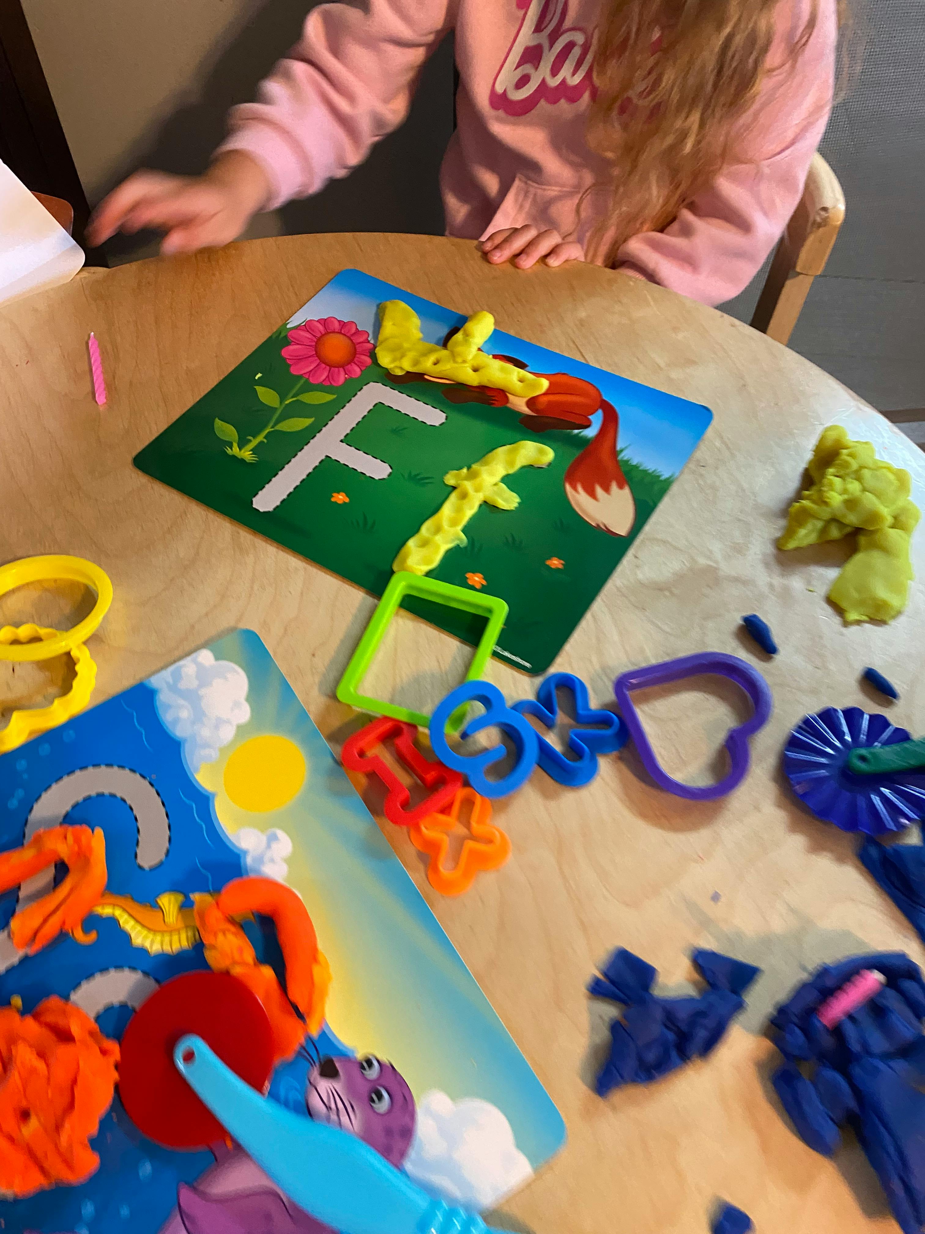 Child playing with play-doh and letter F mat