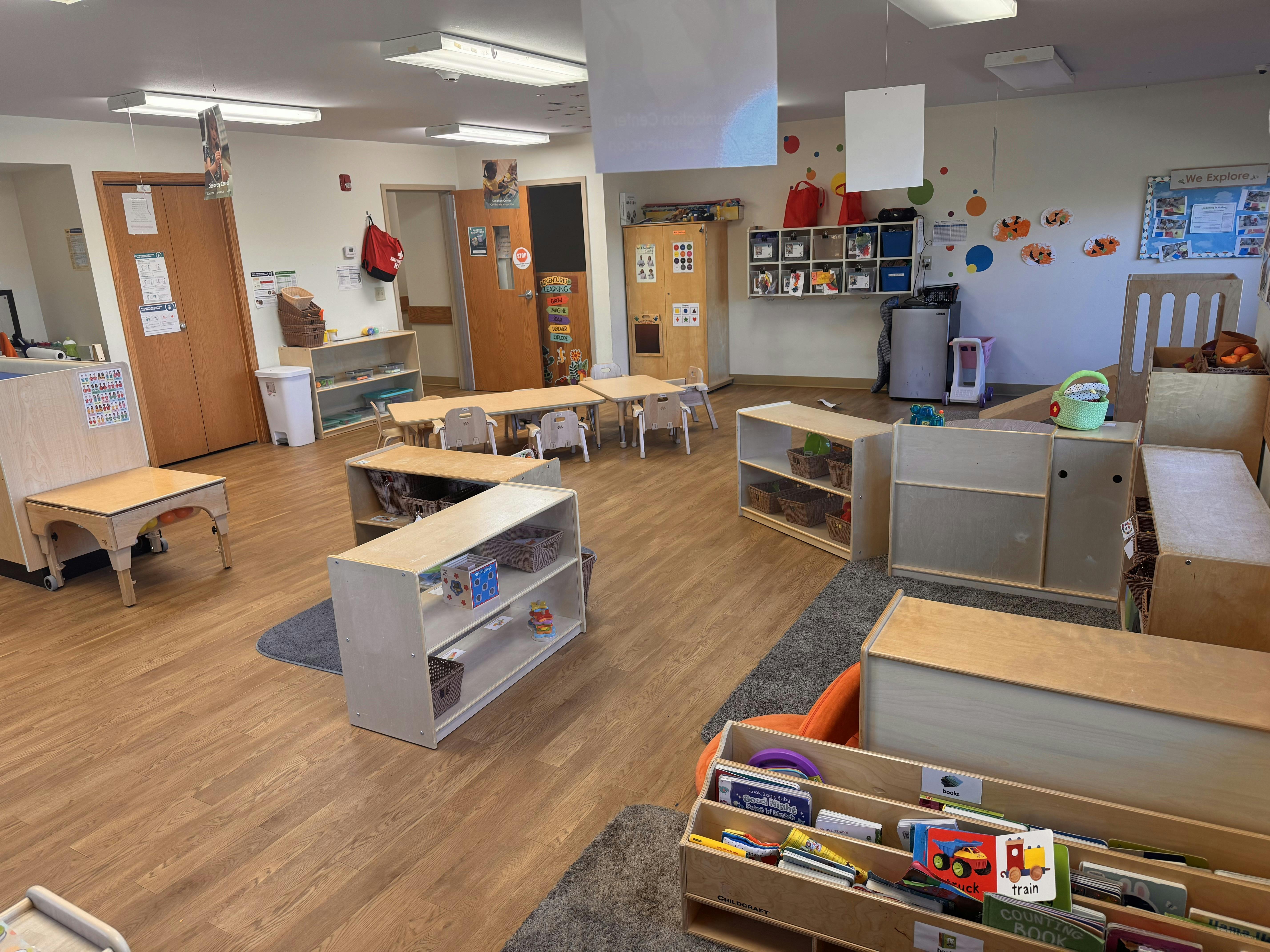 Empty classroom with small tables, chairs, and shelves
