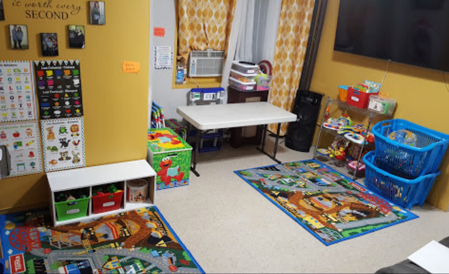 Playroom with colorful rugs, storage bins, and a small table