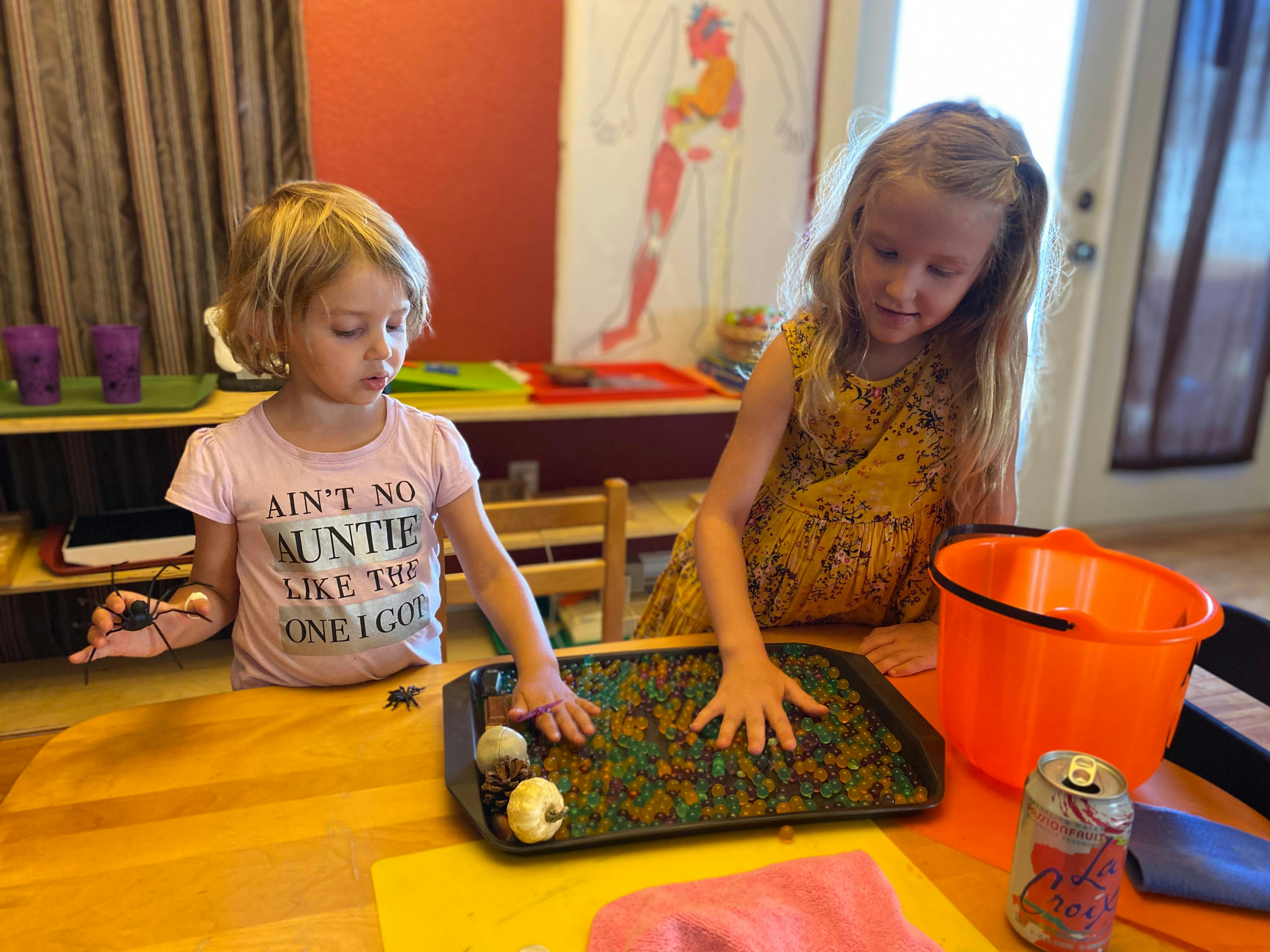 Two children playing with water beads in a tray