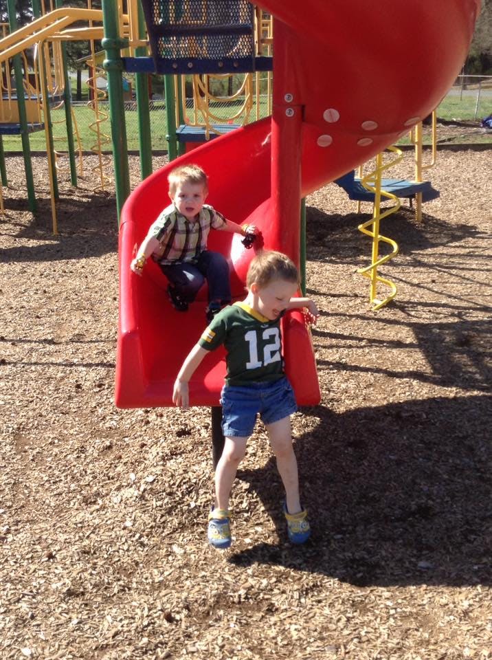 Two children on a red playground slide