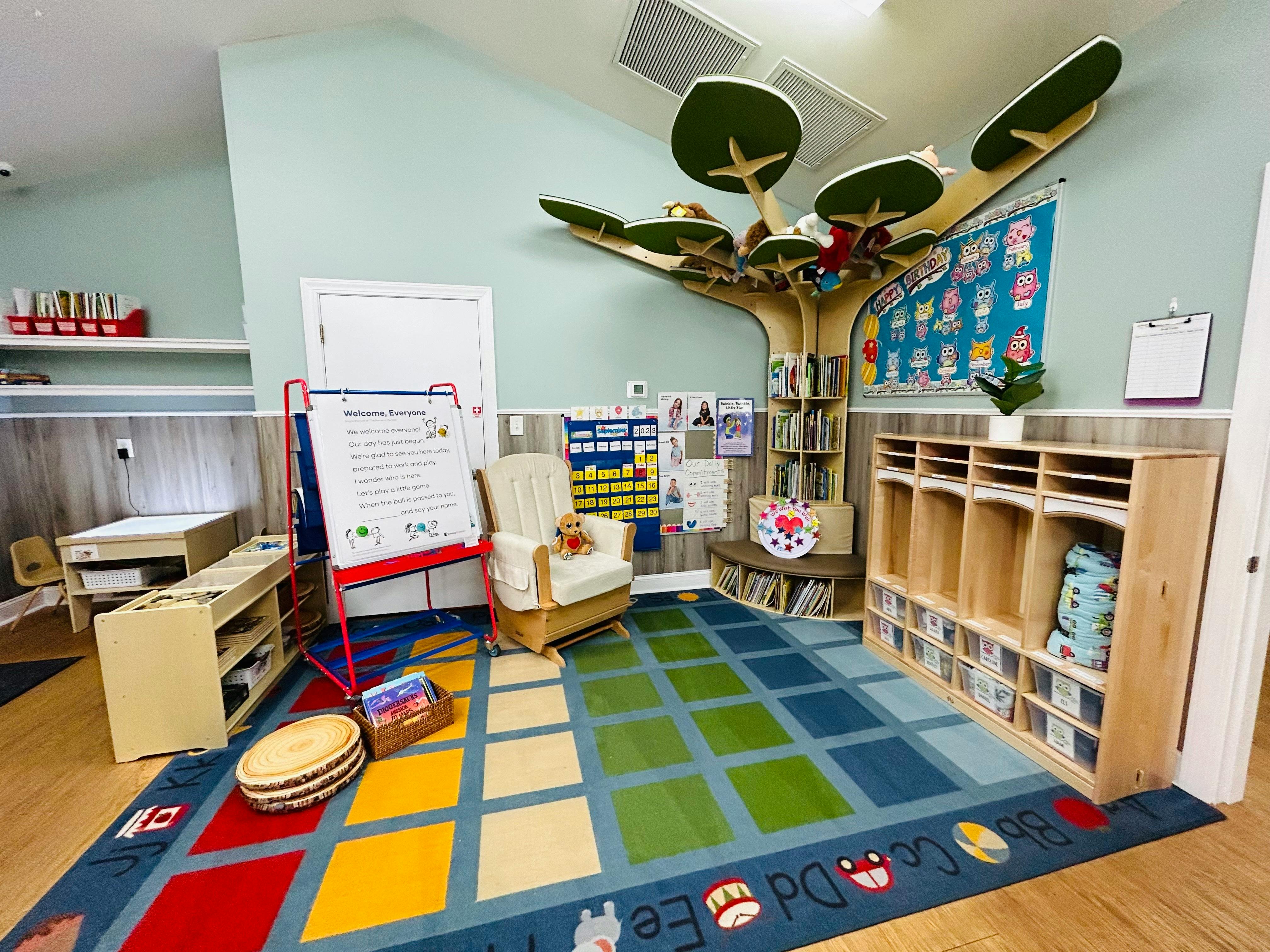 Classroom with a tree-shaped bookshelf, colorful rug, and cubbies